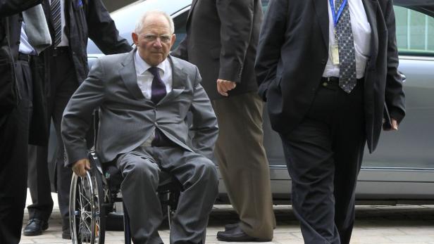Wolfgang Schäuble im Rollstuhl, umgeben von mehreren Personen in Anzügen.