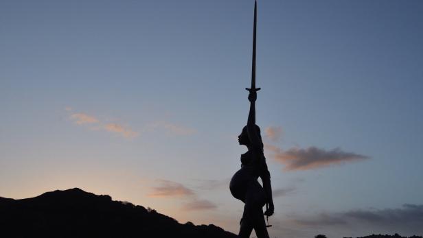 Eine Statue einer schwangeren Frau, die ein Schwert in den Himmel reckt.