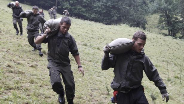 Eine Gruppe Soldaten trägt Sandsäcke einen Hügel hinauf.
