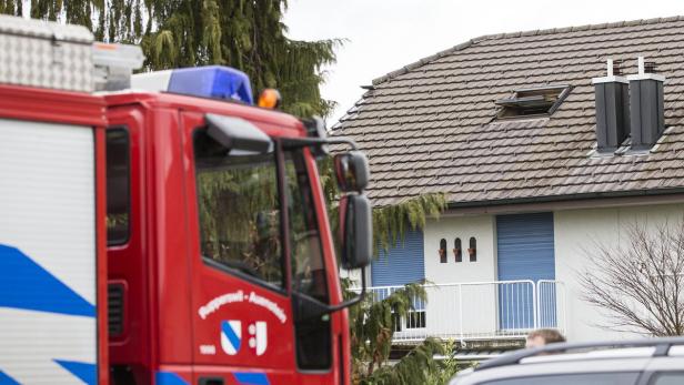 Ein rotes Feuerwehrauto steht vor einem Wohnhaus mit braunem Ziegeldach.