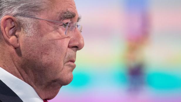 Ein Mann mit Brille im Profil vor einem farbigen Hintergrund.