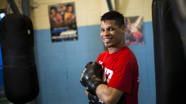 Ein lächelnder Boxer mit Boxhandschuhen in einem Boxstudio.