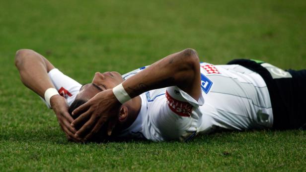 Ein Fußballspieler liegt enttäuscht auf dem Rasen.
