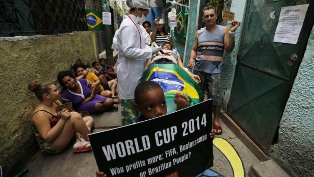 Eine medizinische Fachkraft behandelt eine Person, die in eine brasilianische Flagge gehüllt ist, während Demonstranten gegen die FIFA Fussball-Weltmeisterschaft 2014 protestieren.