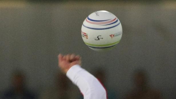 Ein Ball mit roten, blauen und grünen Streifen schwebt über einer Hand.