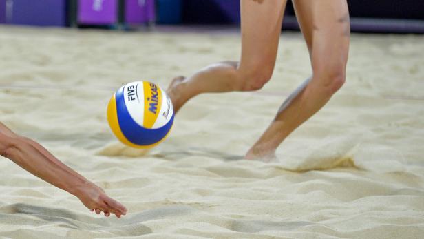 Eine Beachvolleyballspielerin baggert einen Ball im Sand.