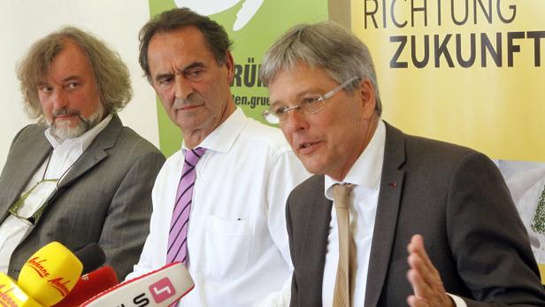 Drei Männer in Anzügen stehen vor einem Banner mit der Aufschrift „Richtung Zukunft“.