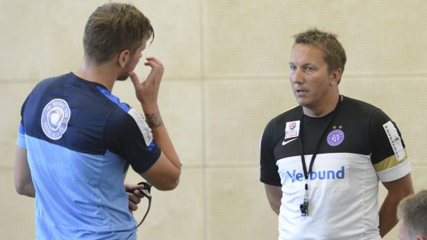 Ein Fußballtrainer bespricht sich mit einem Spieler.