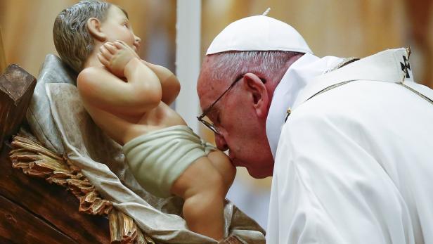 Papst Franziskus küsst eine Jesuskind-Figur.
