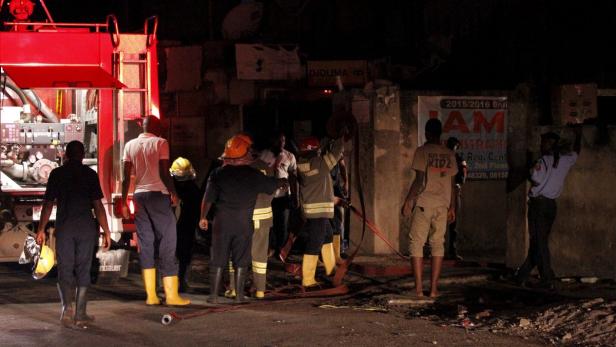 Feuerwehrleute arbeiten nachts an einem Brandort mit einem roten Feuerwehrauto.