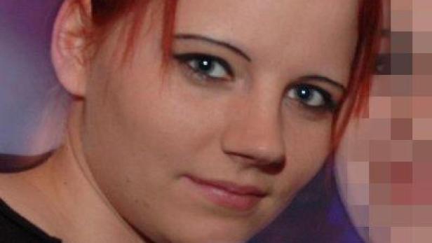 Eine Frau mit roten Haaren und blaugrünen Augen lächelt.
