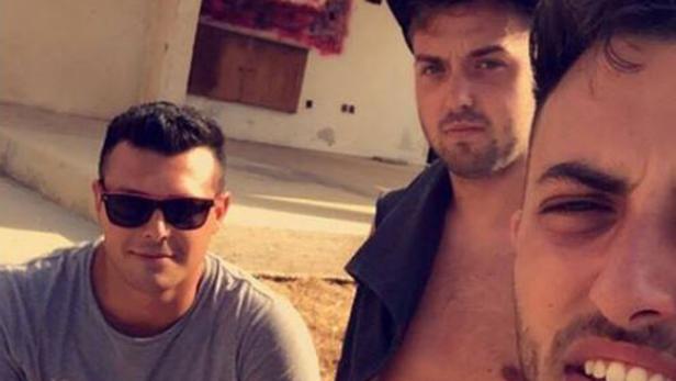 Drei junge Männer posieren für ein Selfie im Freien.