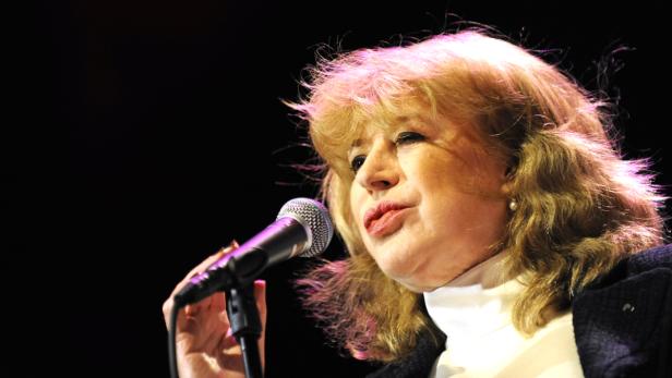 Eine Frau mit blonden Haaren singt in ein Mikrofon.