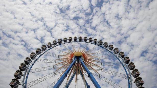 Ein blaues Riesenrad vor einem Himmel mit vielen Wolken.