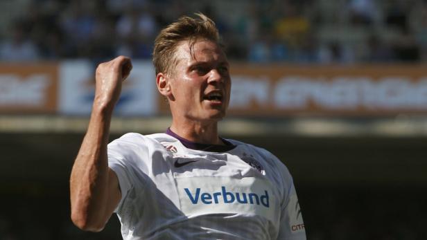 Ein Fußballspieler jubelt mit erhobener Faust auf dem Spielfeld.