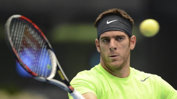 Ein Tennisspieler mit Stirnband schlägt einen Ball mit seinem Schläger.