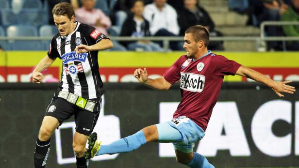 Zwei Fußballspieler im Zweikampf während eines Spiels.