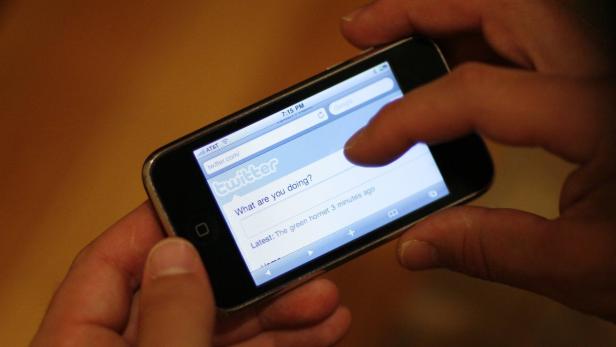Eine Person tippt auf einem älteren iPhone mit der Twitter-App.