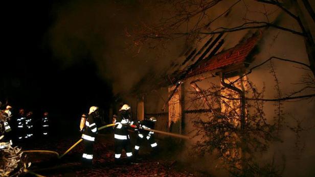 Feuerwehrleute löschen ein brennendes Gebäude in der Nacht.
