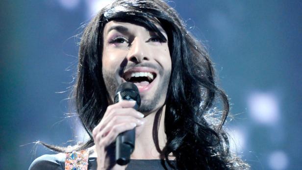 Conchita Wurst singt mit einem Mikrofon in der Hand.