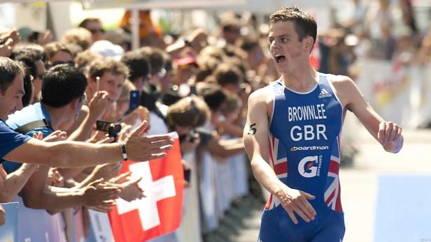 Alistair Brownlee läuft bei einem Triathlon an Zuschauern mit Schweizer Flaggen vorbei.