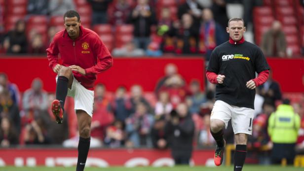 Zwei Fußballspieler wärmen sich auf dem Spielfeld auf.