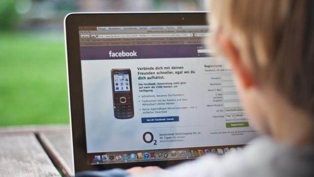 Eine Person betrachtet einen Laptop-Bildschirm mit der Facebook-Anmeldeseite.