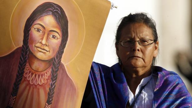 Eine Frau hält ein Bild der Heiligen Kateri Tekakwitha.