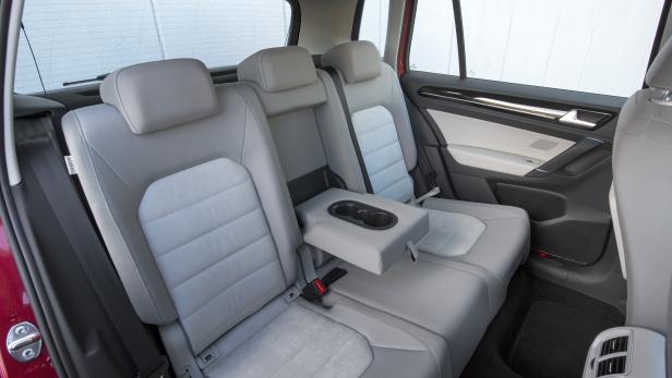 Die Rücksitze eines Autos mit heruntergeklappter Mittelarmlehne und Getränkehaltern.