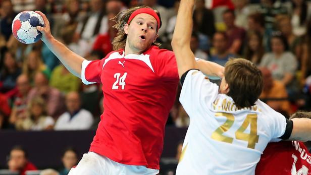 Ein Handballspieler im roten Trikot mit der Nummer 24 wirft den Ball.
