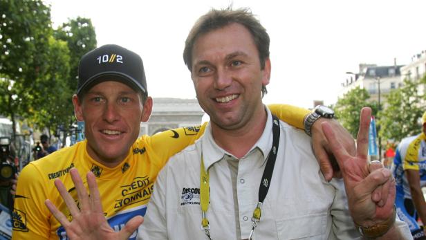 Lance Armstrong und ein Mann posieren vor dem Arc de Triomphe in Paris.