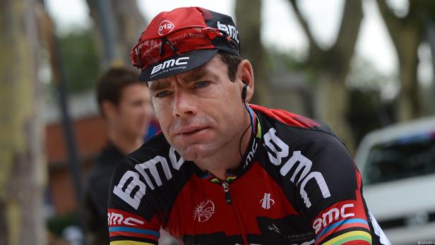 Ein Radrennfahrer in Sportkleidung der Marke BMC mit Kopfhörern.