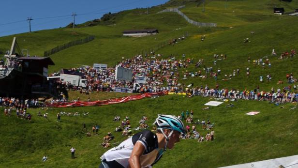Ein Radfahrer fährt einen steilen Hügel hinauf, während viele Zuschauer am Hang stehen.