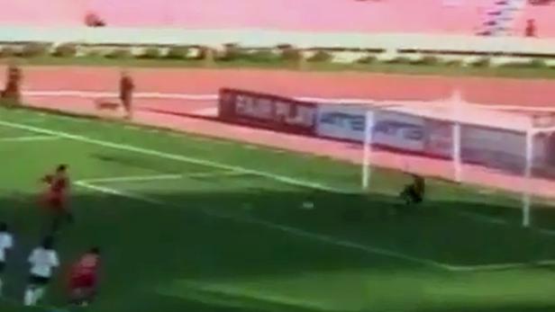 Ein Fußballspieler schießt auf das Tor, während der Torwart versucht, den Ball zu halten.