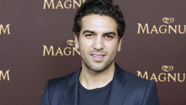 Elyas M'Barek posiert vor einer Wand mit Magnum-Logos.