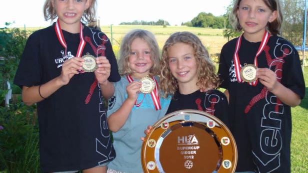 Vier junge Mädchen präsentieren stolz ihre Medaillen und eine Trophäe des HLA Supercup Sieger 2012.