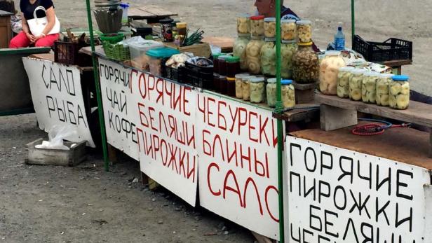 Ein Marktstand unter einem blauen Zelt bietet eingelegtes Gemüse und russische Spezialitäten an.