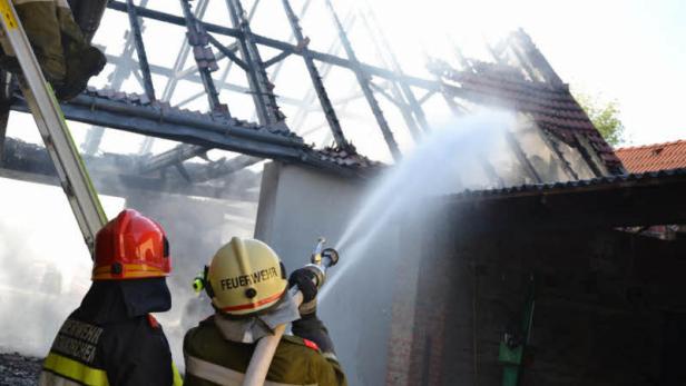 Zwei Feuerwehrleute löschen ein brennendes Gebäude.