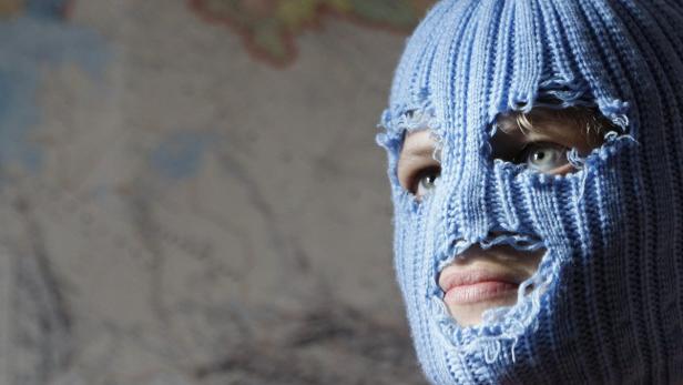 Eine Person trägt eine blaue, zerrissene Sturmhaube.