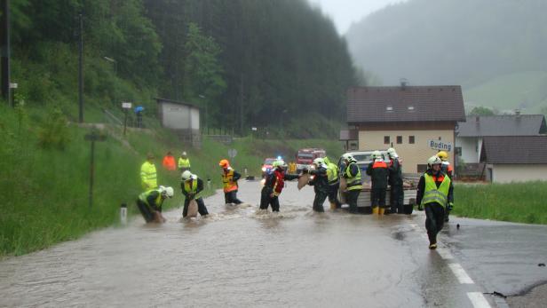 Einsatzkräfte füllen Sandsäcke in einer überfluteten Straße in Böding.