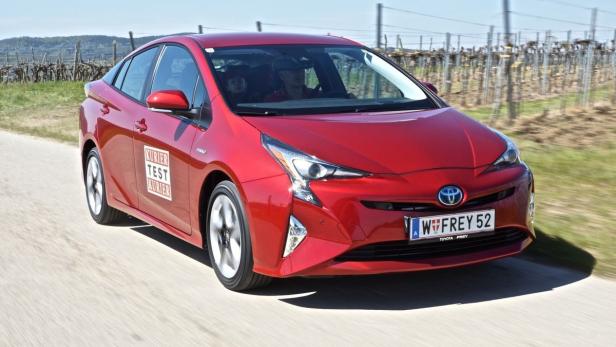 Ein roter Toyota Prius fährt auf einer Landstraße.