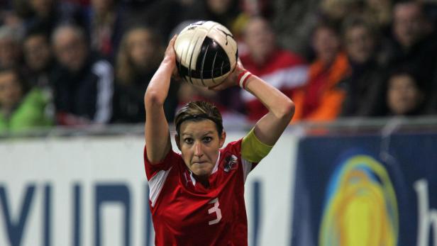 Eine österreichische Fußballspielerin wirft einen Ball beim Einwurf ins Spiel.