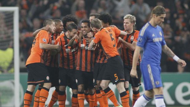 Fußballspieler von Schachtar Donezk feiern ein Tor, während ein Chelsea-Spieler abseits steht.