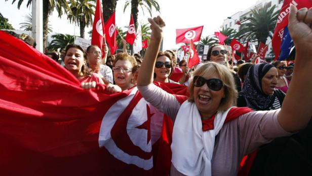 Eine Menschenmenge demonstriert mit tunesischen Flaggen.