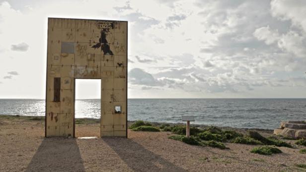 Eine Installation in Form eines Tores steht an einer Küste.