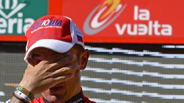 Ein Radfahrer mit einer Kappe des Teams Katusha verdeckt sein Gesicht.