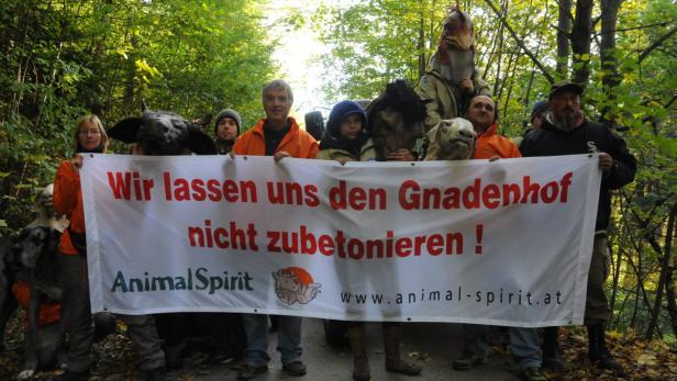 Eine Gruppe von Tierschützern demonstriert mit Tiermasken und einem Banner gegen die Zubetonierung eines Gnadenhofs.