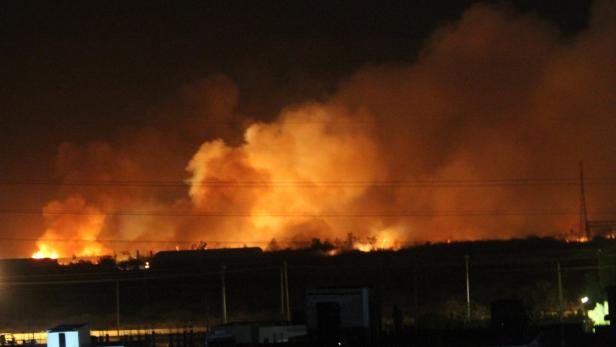 In der Nacht wüten Flammen und Rauch über einem Feld.