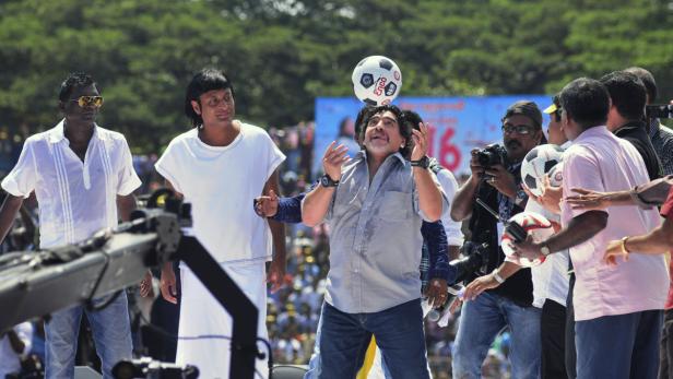 Diego Maradona jongliert einen Fußball vor einer Menschenmenge.