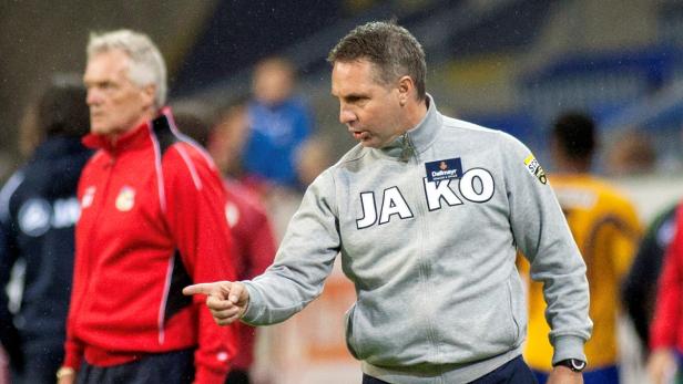 Ein Fußballtrainer gestikuliert während eines Spiels.